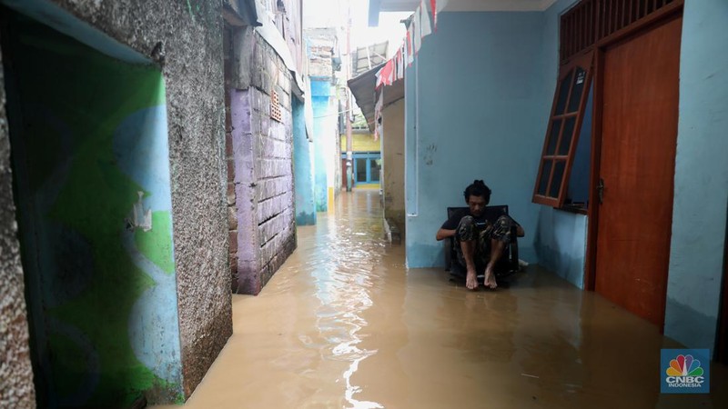 Warga melintas di kawasan banjir di Rawajati, Jakarta, Senin, (10/10). Banjir ini terjadi akibat luapan sungai Ciliwung. (CNBC Indonesia/Muhammad Sabki)
