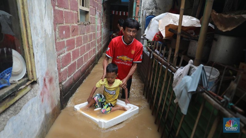 Warga melintas di kawasan banjir di Rawajati, Jakarta, Senin, (10/10). Banjir ini terjadi akibat luapan sungai Ciliwung. (CNBC Indonesia/Muhammad Sabki)