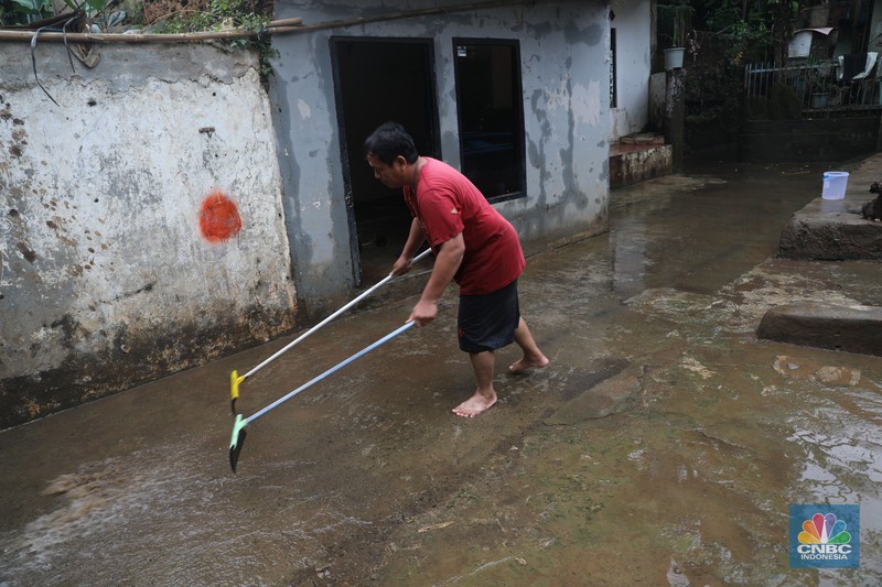 Warga menyapu sisa lumpur usai banjir di kawasan Bidara Cina, Jatinegara, Senin (10/10). (CNBC Indonesia/Muhammad Sabki)
