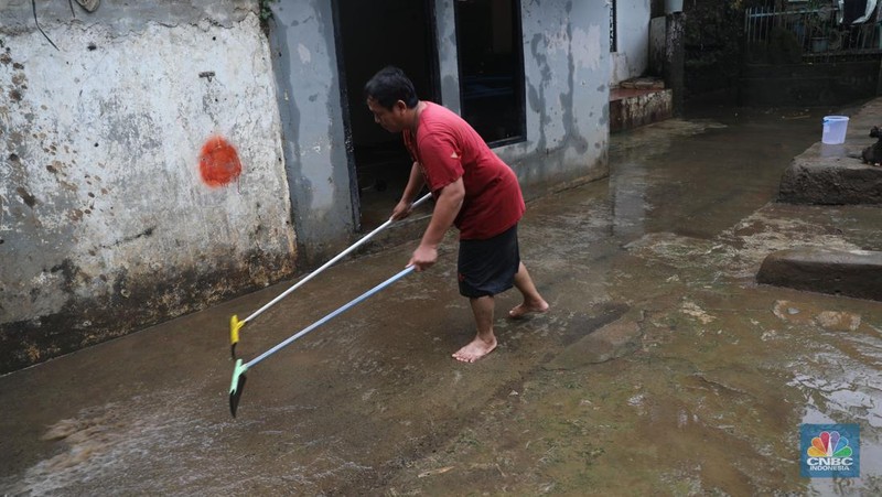 Warga menyapu sisa lumpur usai banjir di kawasan Bidara Cina, Jatinegara, Senin (10/10). (CNBC Indonesia/Muhammad Sabki)
