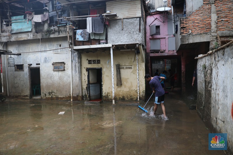 Warga menyapu sisa lumpur usai banjir di kawasan Bidara Cina, Jatinegara, Senin (10/10). (CNBC Indonesia/Muhammad Sabki)