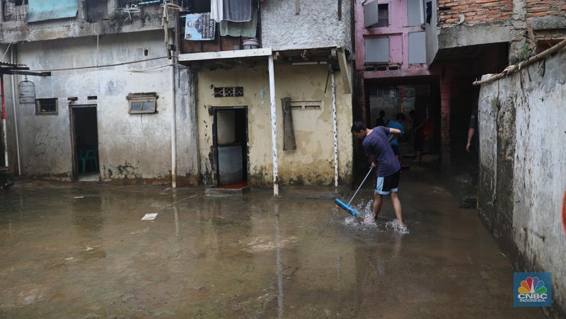 Warga menyapu sisa lumpur usai banjir di kawasan Bidara Cina, Jatinegara, Senin (10/10). (CNBC Indonesia/Muhammad Sabki)