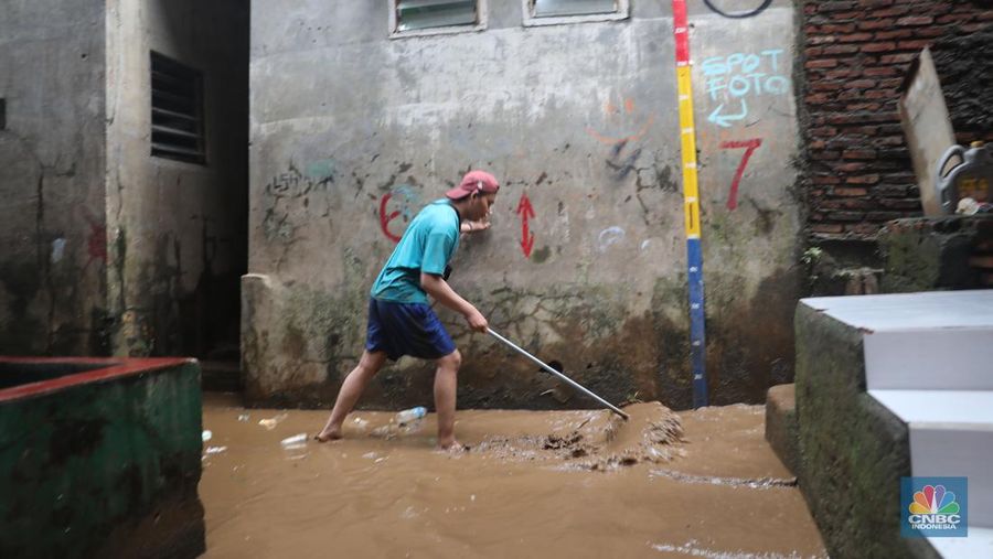 Warga menyapu sisa lumpur usai banjir di kawasan Bidara Cina, Jatinegara, Senin (10/10). (CNBC Indonesia/Muhammad Sabki)