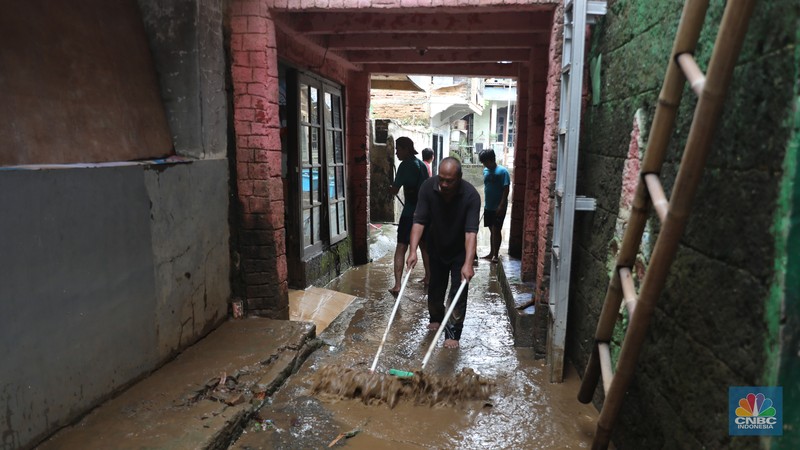 Warga menyapu sisa lumpur usai banjir di kawasan Bidara Cina, Jatinegara, Senin (10/10). (CNBC Indonesia/Muhammad Sabki)