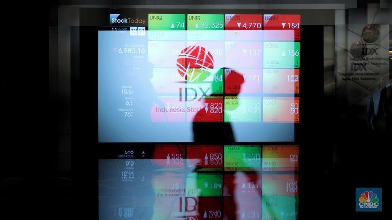 Karyawan melintas di samping layar elektronik yang menunjukkan pergerakan Indeks Harga Saham Gabungan (IHSG) di Bursa Efek Indonesia, Jakarta, Selasa (11/10/2022). (CNBC Indonesia/Andrean Kristianto)