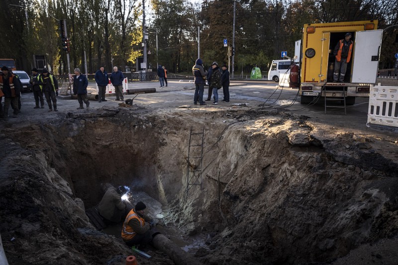 KYIV, UKRAINE - OCTOBER 11: Men fix a pipe in the crater left by a missile strike the day before near Taras Shevchenko National University on October 11, 2022 in Kyiv, Ukraine. Ukraine's emergency services said that 19 people were killed across the country yesterday in a widespread Russian attack on major cities, including the capital. (Photo by Ed Ram/Getty Images)