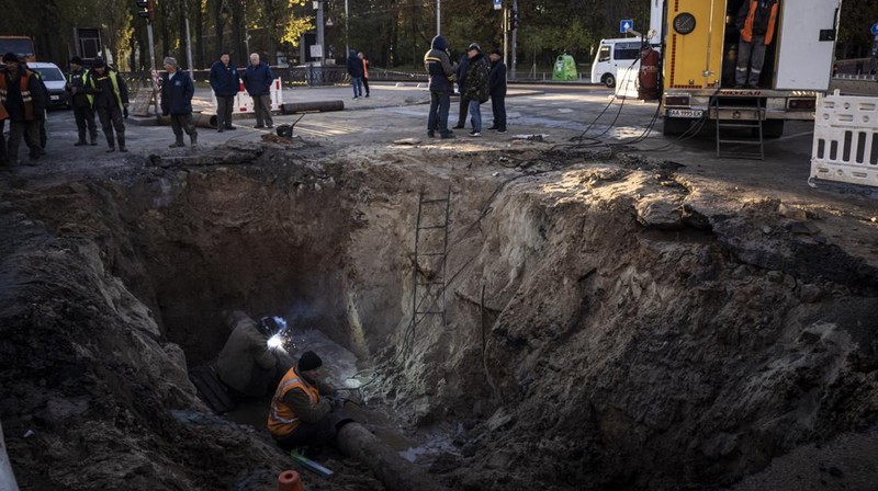 KYIV, UKRAINE - OCTOBER 11: Men fix a pipe in the crater left by a missile strike the day before near Taras Shevchenko National University on October 11, 2022 in Kyiv, Ukraine. Ukraine's emergency services said that 19 people were killed across the country yesterday in a widespread Russian attack on major cities, including the capital. (Photo by Ed Ram/Getty Images)