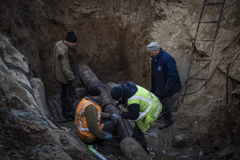 KYIV, UKRAINE - OCTOBER 11: Men fix a pipe in the crater left by a missile strike the day before near Taras Shevchenko National University on October 11, 2022 in Kyiv, Ukraine. Ukraine's emergency services said that 19 people were killed across the country yesterday in a widespread Russian attack on major cities, including the capital. (Photo by Ed Ram/Getty Images)