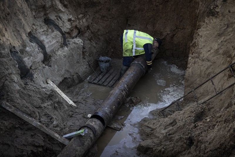 KYIV, UKRAINE - OCTOBER 11: Men fix a pipe in the crater left by a missile strike the day before near Taras Shevchenko National University on October 11, 2022 in Kyiv, Ukraine. Ukraine's emergency services said that 19 people were killed across the country yesterday in a widespread Russian attack on major cities, including the capital. (Photo by Ed Ram/Getty Images)