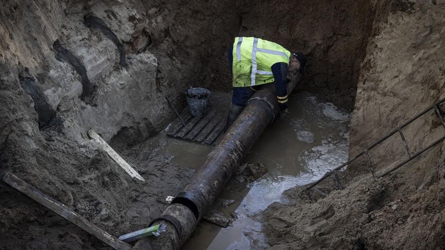 KYIV, UKRAINE - OCTOBER 11: Men fix a pipe in the crater left by a missile strike the day before near Taras Shevchenko National University on October 11, 2022 in Kyiv, Ukraine. Ukraine's emergency services said that 19 people were killed across the country yesterday in a widespread Russian attack on major cities, including the capital. (Photo by Ed Ram/Getty Images)