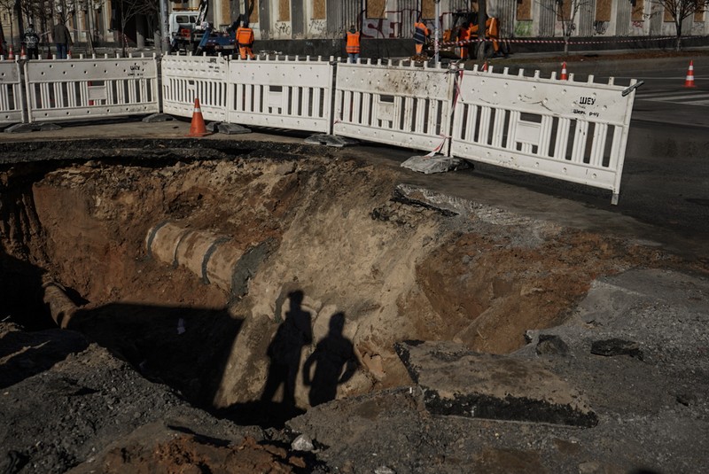 KYIV, UKRAINE - OCTOBER 11: Men fix a pipe in the crater left by a missile strike the day before near Taras Shevchenko National University on October 11, 2022 in Kyiv, Ukraine. Ukraine's emergency services said that 19 people were killed across the country yesterday in a widespread Russian attack on major cities, including the capital. (Photo by Ed Ram/Getty Images)