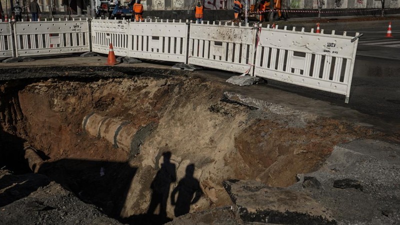 KYIV, UKRAINE - OCTOBER 11: Men fix a pipe in the crater left by a missile strike the day before near Taras Shevchenko National University on October 11, 2022 in Kyiv, Ukraine. Ukraine's emergency services said that 19 people were killed across the country yesterday in a widespread Russian attack on major cities, including the capital. (Photo by Ed Ram/Getty Images)