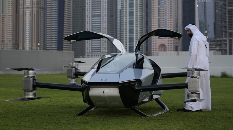 People look at the XPeng X2, an electric flying taxi developed by the Guangzhou-based XPeng, Inc's aviation affiliate, being tested in front of the Marina District in Dubai, United Arab Emirates, Monday, Oct. 10, 2022. Monday’s demonstration was held with an empty cockpit, but the company says it carried out a manned flight test last year of the two-passenger vehicle. (AP Photo/Kamran Jebreili)