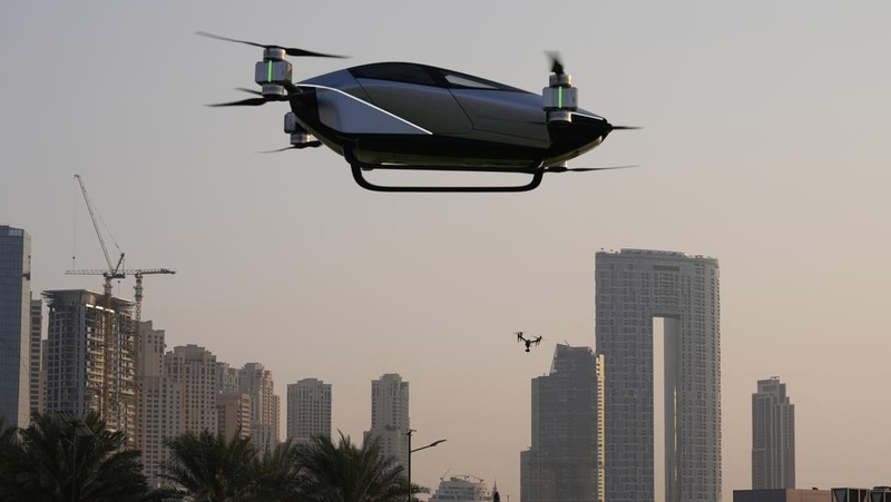People look at the XPeng X2, an electric flying taxi developed by the Guangzhou-based XPeng, Inc's aviation affiliate, being tested in front of the Marina District in Dubai, United Arab Emirates, Monday, Oct. 10, 2022. Monday’s demonstration was held with an empty cockpit, but the company says it carried out a manned flight test last year of the two-passenger vehicle. (AP Photo/Kamran Jebreili)