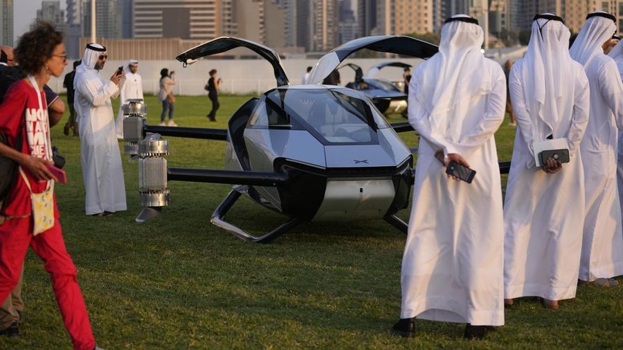 People look at the XPeng X2, an electric flying taxi developed by the Guangzhou-based XPeng, Inc's aviation affiliate, being tested in front of the Marina District in Dubai, United Arab Emirates, Monday, Oct. 10, 2022. Monday’s demonstration was held with an empty cockpit, but the company says it carried out a manned flight test last year of the two-passenger vehicle. (AP Photo/Kamran Jebreili)