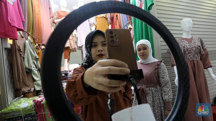 Karyawan mempromosikan pakaian wanita di platfom siaran langsung (live) media sosial di kawasan Pertokoan Tanah Abang, Jakarta Pusat, Kamis (13/10/2022). Di era digital saat ini berbagai cara pedagang mempromosikan barang jualanannya salah satunya dengan platform media sosial. (CNBC Indonesia/Andrean Kristianto)
