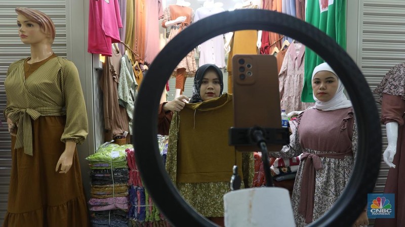 Karyawan mempromosikan pakaian wanita di platfom siaran langsung (live) media sosial di kawasan Pertokoan Tanah Abang, Jakarta Pusat, Kamis (13/10/2022). (CNBC Indonesia/Andrean Kristianto)