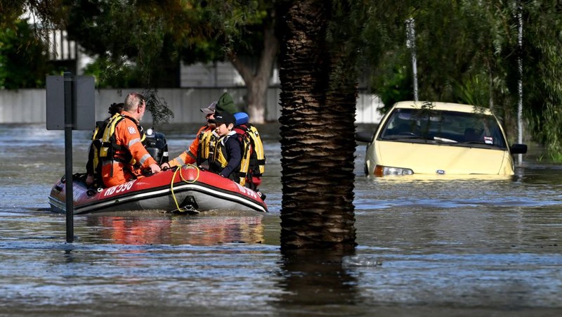 Pekerja darurat mengevakuasi warga saat banjir di pinggiran Melbourne, Maribyrnong, Australia, Jumat (14102/2022). Banjir telah menggenangi jalan, memaksa sekolah ditutup, dan memutus aliran listrik ke 3.000 rumah dan bisnis. (Photo by WILLIAM WEST/AFP via Getty Images)
