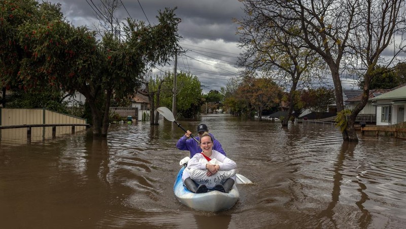 Pekerja darurat mengevakuasi warga saat banjir di pinggiran Melbourne, Maribyrnong, Australia, Jumat (14102/2022). Banjir telah menggenangi jalan, memaksa sekolah ditutup, dan memutus aliran listrik ke 3.000 rumah dan bisnis. (Photo by WILLIAM WEST/AFP via Getty Images)
