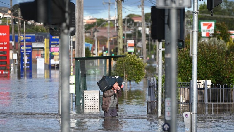 Pekerja darurat mengevakuasi warga saat banjir di pinggiran Melbourne, Maribyrnong, Australia, Jumat (14102/2022). Banjir telah menggenangi jalan, memaksa sekolah ditutup, dan memutus aliran listrik ke 3.000 rumah dan bisnis. (Photo by WILLIAM WEST/AFP via Getty Images)