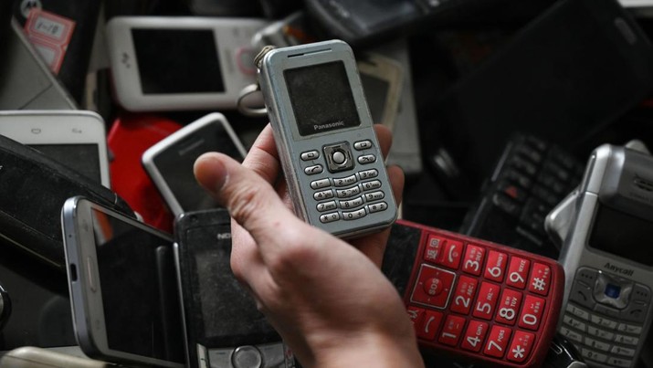 This photo taken on March 20, 2019 shows artist Shen Bolun holding an old mobile phone as he works on an art installation in Beijing. - The sculpture, based on the Tower of Babel and unveiled in a Beijing shopping mall on March 30, is part of a Greenpeace campaign to raise awareness about electronic waste. (Photo by GREG BAKER / AFP)        (Photo credit should read GREG BAKER/AFP via Getty Images)