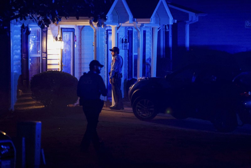 Petugas Polisi Raleigh berjalan dari pintu ke pintu memeriksa penduduk di lingkungan Hedingham dan daerah Jalur Sungai Neuse di Raleigh, North Carolina. Kamis malam (13/10/2022). Sedikitnya lima orang tewas dalam insiden penembakan brutal yang terjadi sekitar pukul 17.00 waktu setempat, di dekat Jalur Hijau Sungai Neus. Atas kejadiaan tersebut satu orang telah ditangkap. (Travis Long/The News & Observer via AP)