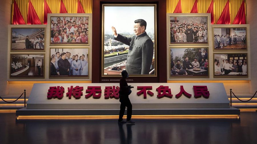Seorang pengunjung berjalan di dekat pajangan yang menunjukkan gambar Presiden China Xi Jinping di Museum Partai Komunis di Beijing, China, Kamis (13/10/2022). Partai Komunis China (PKC) bakal menyelenggarakan kongres lima tahunan mereka yang ke-20 pada 16 Oktober mendatang. (Photo by Kevin Frayer/Getty Images)