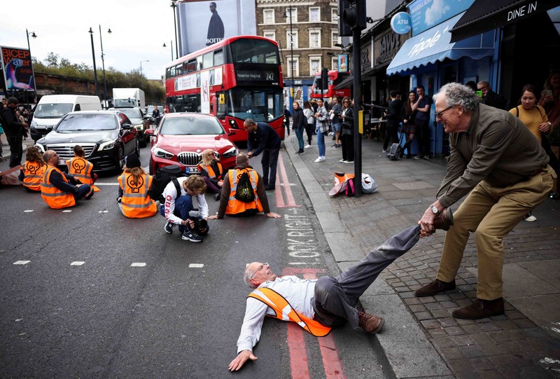 A member of the public drags an activist who is blocking the road during a 