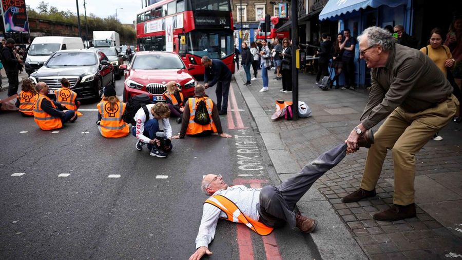 A member of the public drags an activist who is blocking the road during a 