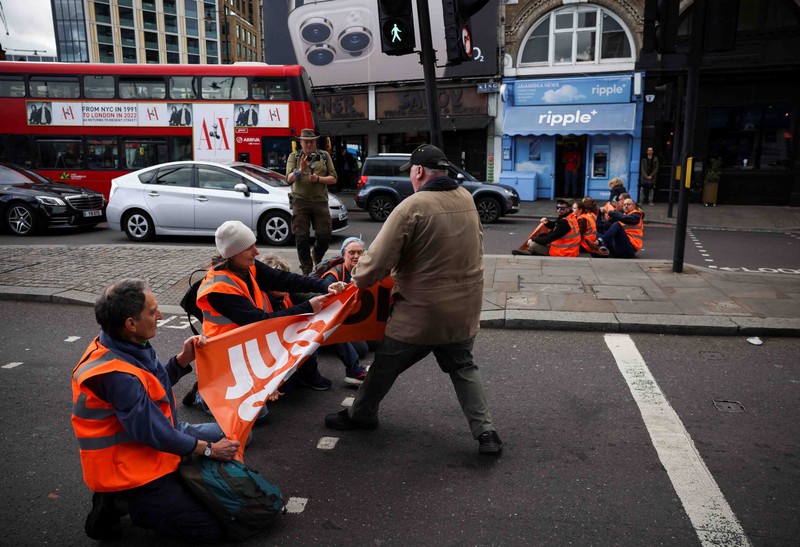 BRITAIN-PROTEST/ A member of the public drags an activist who is blocking the road during a