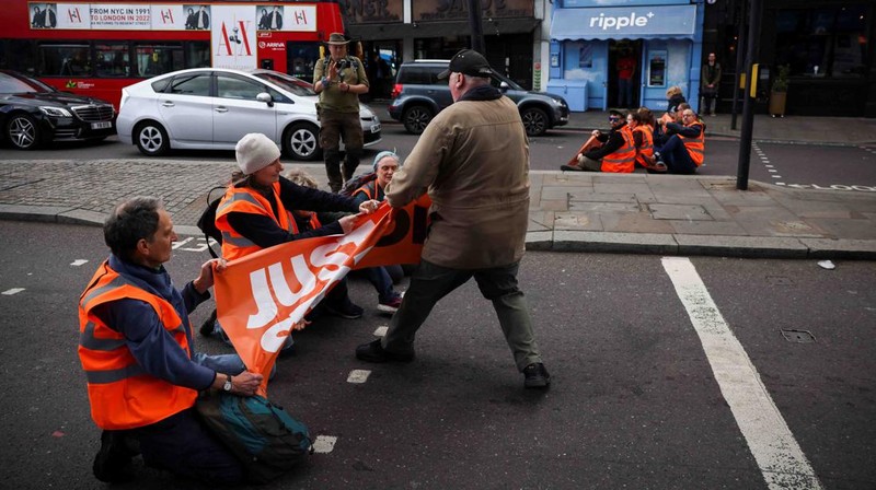 A member of the public drags an activist who is blocking the road during a 
