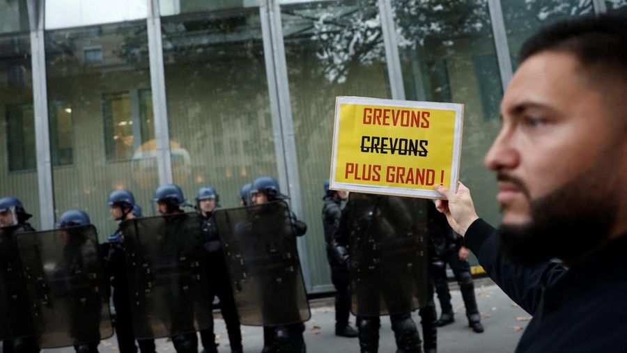 A demonstrator destroys a bank window during clashes at a demonstration in Paris as part of a nationwide day of strike and protests for higher wages and against requisitions at refineries in France, October 18, 2022.  REUTERS/Benoit Tessier