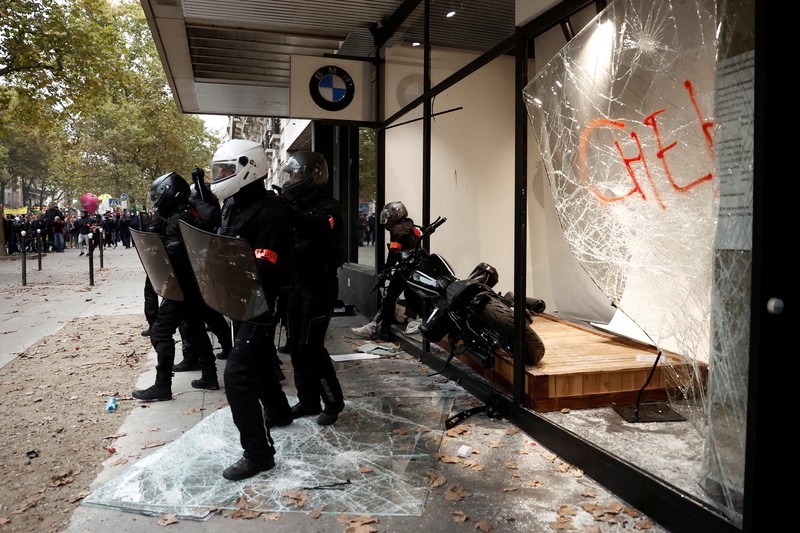 FRANCE-STRIKE/PROTEST A demonstrator destroys a bank window during clashes at a demonstration in Paris as part of a nationwide day of strike and protests for higher wages and against requisitions at refineries in France, October 18, 2022. REUTERS/Benoit Tessier