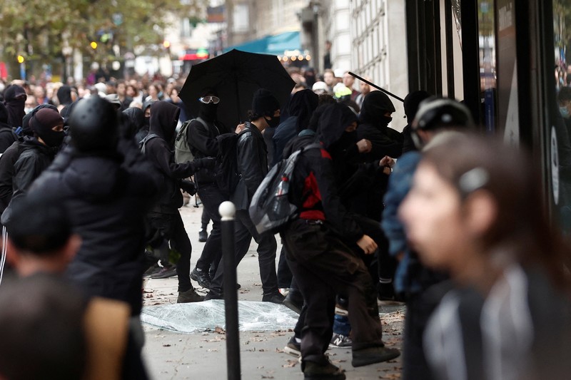 FRANCE-STRIKE/PROTEST A demonstrator destroys a bank window during clashes at a demonstration in Paris as part of a nationwide day of strike and protests for higher wages and against requisitions at refineries in France, October 18, 2022. REUTERS/Benoit Tessier