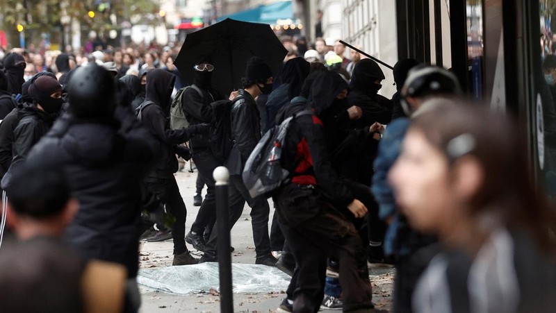 A demonstrator destroys a bank window during clashes at a demonstration in Paris as part of a nationwide day of strike and protests for higher wages and against requisitions at refineries in France, October 18, 2022.  REUTERS/Benoit Tessier