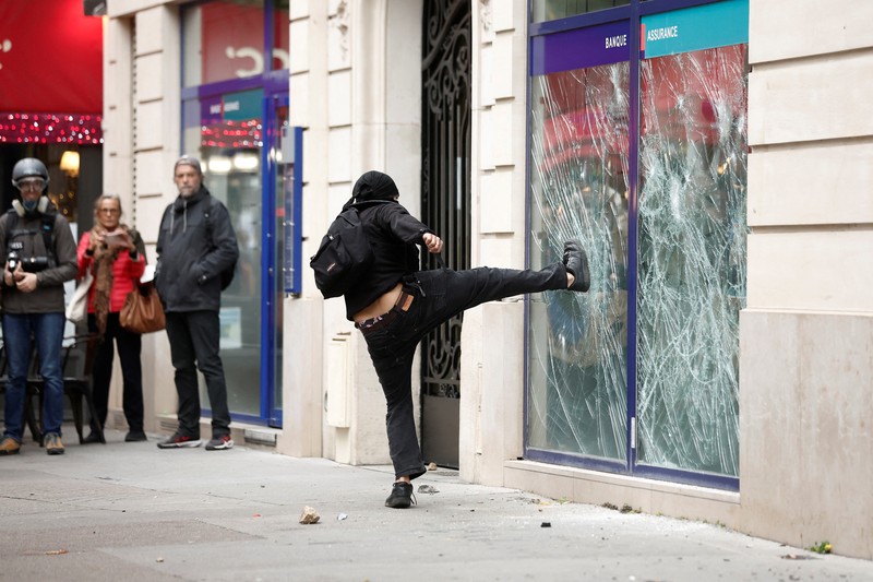 A demonstrator destroys a bank window during clashes at a demonstration in Paris as part of a nationwide day of strike and protests for higher wages and against requisitions at refineries in France, October 18, 2022.  REUTERS/Benoit Tessier
