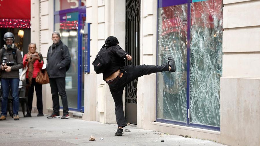 A demonstrator destroys a bank window during clashes at a demonstration in Paris as part of a nationwide day of strike and protests for higher wages and against requisitions at refineries in France, October 18, 2022.  REUTERS/Benoit Tessier