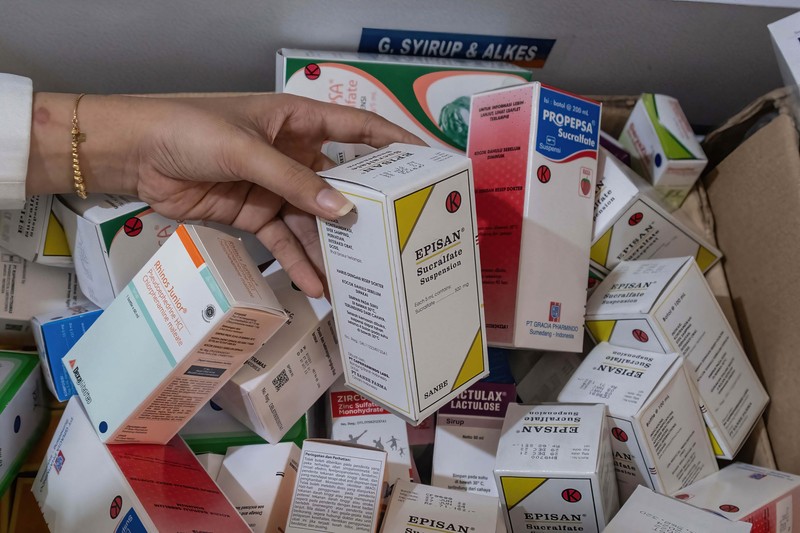 KENDARI, SOUTH EAST SULAWESI, INDONESIA - 2022/10/20: A pharmacist unloads a line of syrup-type drugs from a sales shelf at a pharmacy. Ministry of Health gave instructions not to give or temporarily prescribe drugs over-the-counter in the form of syrup to the public due to atypical cases of progressive acute kidney failure is occurring in children in Indonesia. (Photo by Andry Denisah/SOPA Images/LightRocket via Getty Images)