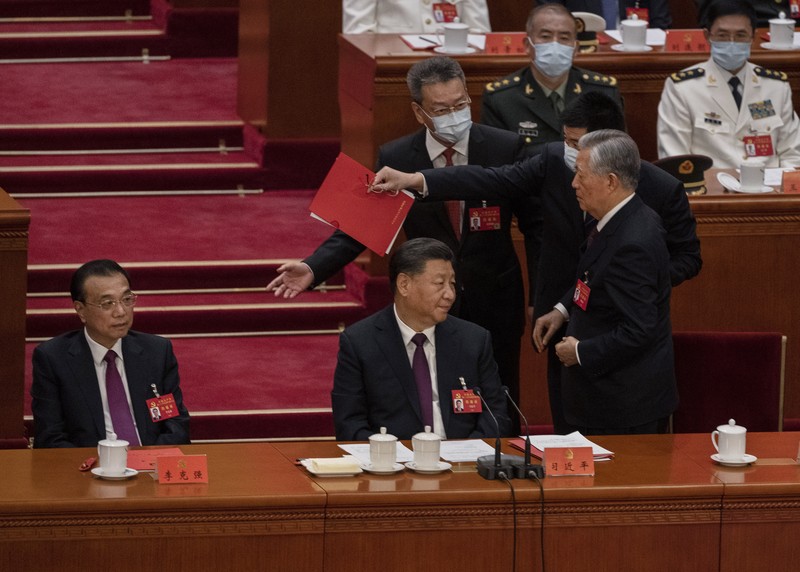 Presiden Tiongkok Xi Jinping, kanan, mendengarkan bantuan saat dia duduk di sebelah Perdana Menteri Li Keqiang selama sesi penutupan Kongres Nasional Partai Komunis Tiongkok ke-20, di Aula Besar Rakyat pada Oktober 22, 2022 di Beijing, Cina. (Getty Images/Kevin Frayer)