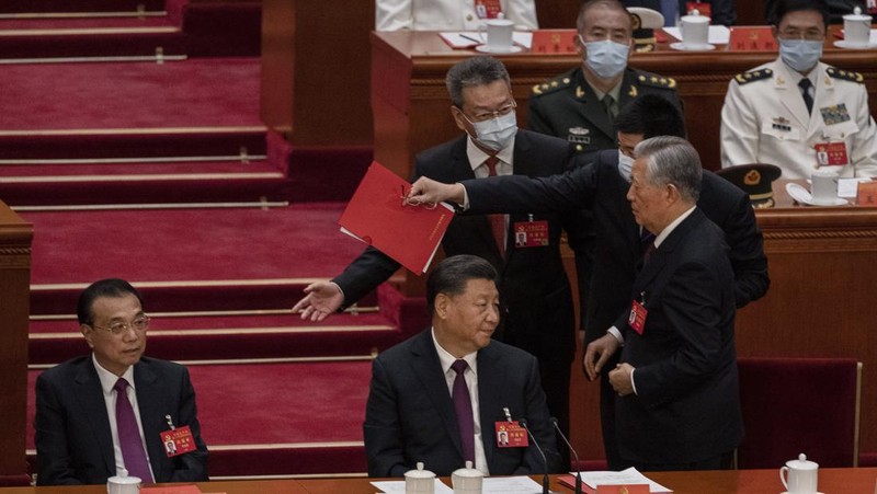 Presiden Tiongkok Xi Jinping, kanan, mendengarkan bantuan saat dia duduk di sebelah Perdana Menteri Li Keqiang selama sesi penutupan Kongres Nasional Partai Komunis Tiongkok ke-20, di Aula Besar Rakyat pada Oktober 22, 2022 di Beijing, Cina. (Getty Images/Kevin Frayer)