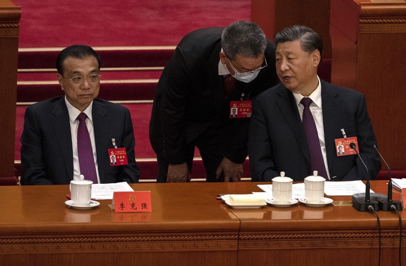 Presiden Tiongkok Xi Jinping, kanan, mendengarkan bantuan saat dia duduk di sebelah Perdana Menteri Li Keqiang selama sesi penutupan Kongres Nasional Partai Komunis Tiongkok ke-20, di Aula Besar Rakyat pada Oktober 22, 2022 di Beijing, Cina. (Getty Images/Kevin Frayer)