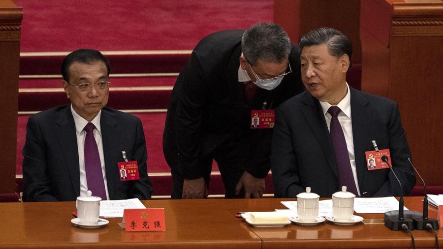 Presiden Tiongkok Xi Jinping, kanan, mendengarkan bantuan saat dia duduk di sebelah Perdana Menteri Li Keqiang selama sesi penutupan Kongres Nasional Partai Komunis Tiongkok ke-20, di Aula Besar Rakyat pada Oktober 22, 2022 di Beijing, Cina. (Getty Images/Kevin Frayer)