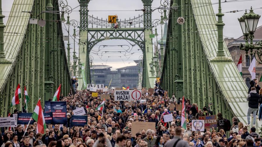Para pengunjuk rasa memegang spanduk selama pawai simpati melintasi Jembatan Liberty untuk menunjukkan dukungan mereka kepada para guru di Budapest, Hongaria, Minggu (23/10/2022). Pada tanggal 23 Oktober, orang-orang Hongaria memperingati dimulainya revolusi 1956 yang membuat negara itu melepaskan diri dari pengaruh Soviet, ketika para mahasiswa di Budapest menuntut reformasi politik. (Photo by Janos Kummer/Getty Images)