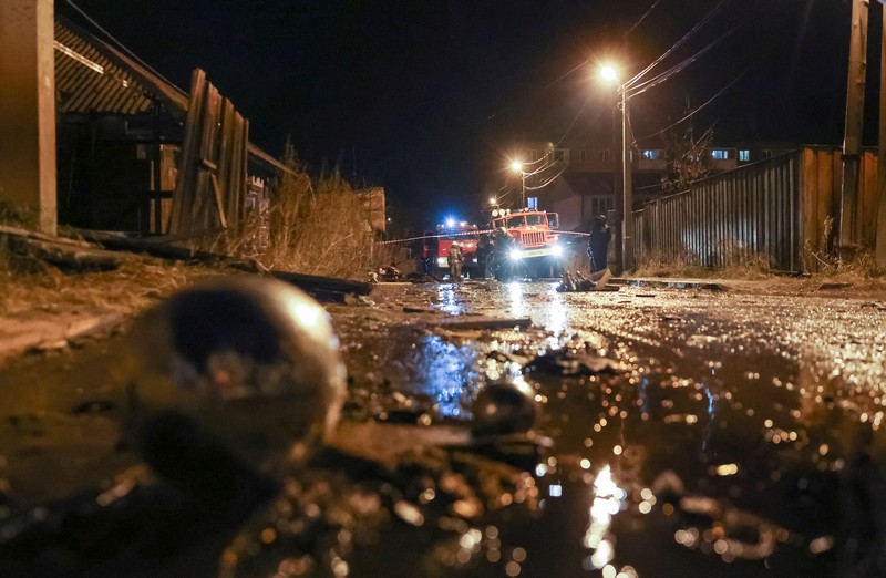 Orang-orang melihat puing-puing pesawat militer Rusia yang jatuh dan menabrak bangunan perumahan di kota Irkutsk, Rusia, Minggu (23/10/2022). Para pejabat mengatakan pesawat itu adalah pesawat tempur Sukhoi Su-30 dalam uji terbang dan menabrak sebuah rumah berlantai dua di kota itu. (REUTERS/Stringer)