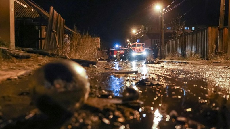 Orang-orang melihat puing-puing pesawat militer Rusia yang jatuh dan menabrak bangunan perumahan di kota Irkutsk, Rusia, Minggu (23/10/2022). Para pejabat mengatakan pesawat itu adalah pesawat tempur Sukhoi Su-30 dalam uji terbang dan menabrak sebuah rumah berlantai dua di kota itu. (REUTERS/Stringer)