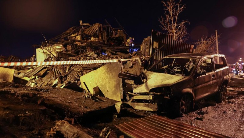 Orang-orang melihat puing-puing pesawat militer Rusia yang jatuh dan menabrak bangunan perumahan di kota Irkutsk, Rusia, Minggu (23/10/2022). Para pejabat mengatakan pesawat itu adalah pesawat tempur Sukhoi Su-30 dalam uji terbang dan menabrak sebuah rumah berlantai dua di kota itu. (REUTERS/Stringer)