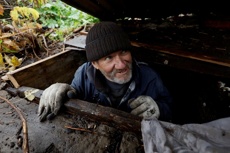 Myhaylo Yurkiv, 65, climbs out of the small bunker he stayed in for six months during fierce battles under Russian occupation which destroyed every home in the village and cut the village in two by the shelling of the bridge, leaving him now as the only person living on his side of the village, as Russia's invasion of Ukraine continues, in Tsupivka, Ukraine, October 26, 2022. REUTERS/Clodagh Kilcoyne     TPX IMAGES OF THE DAY