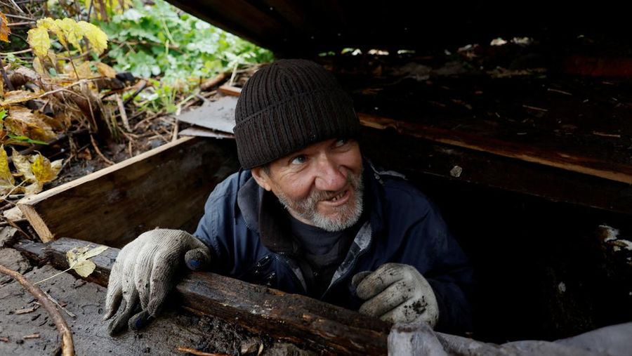 Myhaylo Yurkiv, 65, climbs out of the small bunker he stayed in for six months during fierce battles under Russian occupation which destroyed every home in the village and cut the village in two by the shelling of the bridge, leaving him now as the only person living on his side of the village, as Russia's invasion of Ukraine continues, in Tsupivka, Ukraine, October 26, 2022. REUTERS/Clodagh Kilcoyne     TPX IMAGES OF THE DAY