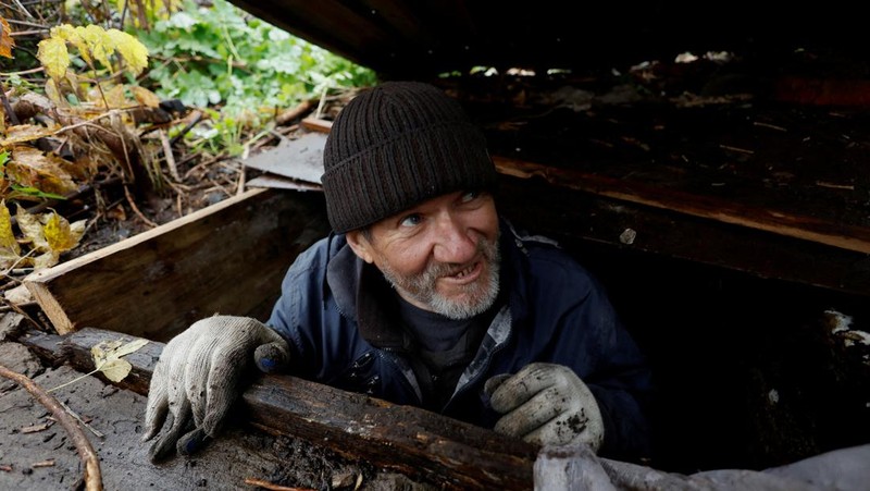 Myhaylo Yurkiv, 65, climbs out of the small bunker he stayed in for six months during fierce battles under Russian occupation which destroyed every home in the village and cut the village in two by the shelling of the bridge, leaving him now as the only person living on his side of the village, as Russia's invasion of Ukraine continues, in Tsupivka, Ukraine, October 26, 2022. REUTERS/Clodagh Kilcoyne     TPX IMAGES OF THE DAY