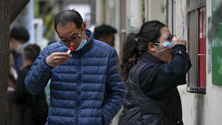 A man looks at his testing tube as a woman gets her routine COVID-19 throat swab at a coronavirus testing site in Beijing, Thursday, Oct. 27, 2022. China's ruling Communist Party has so far shown no sign of easing the 